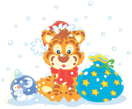 Cute little tiger in a red and white Santa hat sitting on snow with a beautiful gift bag and a Christmas toy ball, vector cartoon illustration isolated on a white backgroundのイラスト素材