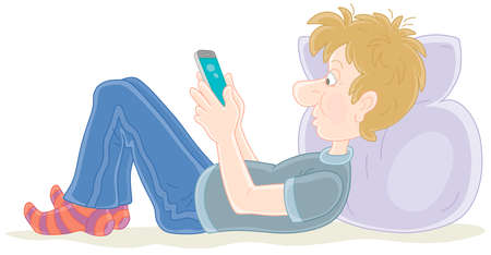 Funny boy lying on his bed and playing with a smartphone, vector cartoon illustration isolated on a white backgroundのイラスト素材