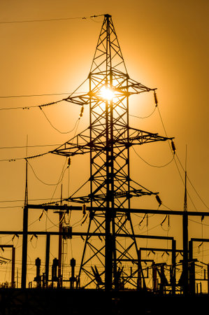 The silhouette of a power line against the background of a bright yellow sunset. Electrical...