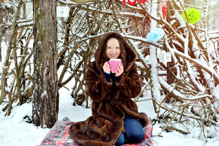 Portrait of a young girl with a cup of tea on a sunny winter day in the park. I want to keep warm. Heat. Horizontal orientation.の写真素材
