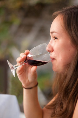 Young woman drinking red wine, side profile 