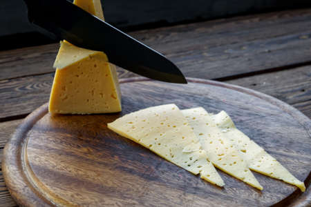 slice cheese on wooden cutting boardの写真素材