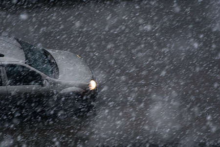 car driving through heavy snow with headlights onの写真素材