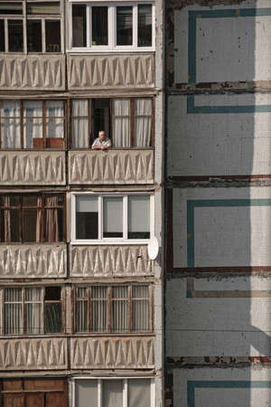 lonely elderly man sitting on the balcony of an apartment building during quarantineのeditorial素材