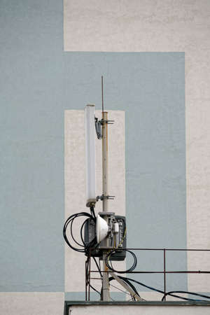 Cellular. A small base transceiver station is not against the wall of a neighboring house. Telecommunication tower. Wireless Transmitter Antenna. Telecommunication tower with antennas.のeditorial素材