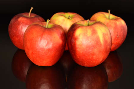 Five red sweet juicy apples, close-up, on a black background.の写真素材