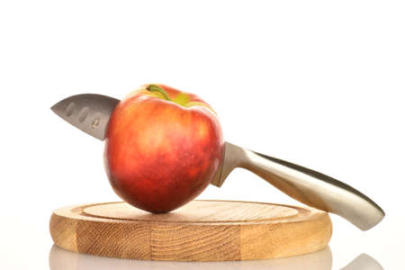 One red juicy apple with a knife on a bamboo tray, close-up, on a white background.の写真素材