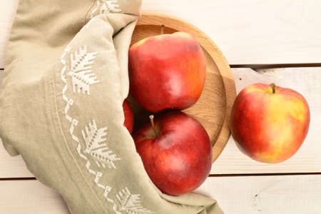 Several red organic apples on a bamboo tray with a linen napkin, on a painted wooden table.の写真素材