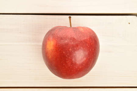 One red fresh apple on a painted wooden table.の写真素材