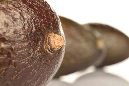 In the foreground, in focus, macro, portion, dark green, ripe organic tasty avocado on a white background. In the background are two whole avocados, out of focus.の写真素材