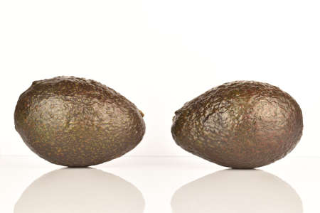 Two whole dark green rounded ripe tasty nutritious avocados on a white background.の写真素材
