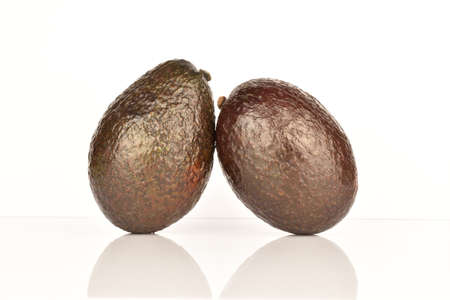 Two whole dark green rounded ripe tasty nutritious avocados on a white background.の写真素材