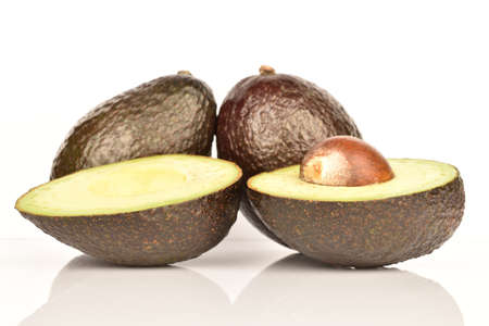 Two whole and two halves, dark green, ripe organic tasty avocado on a white background.の写真素材