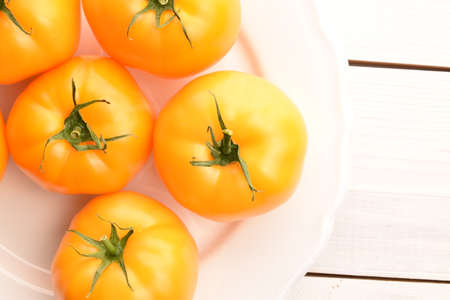 Fresh ripe, yellow tomatoes, close-up, on a painted wooden table.の写真素材