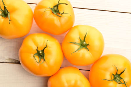 Fresh ripe, yellow tomatoes, close-up, on a painted wooden table.の写真素材