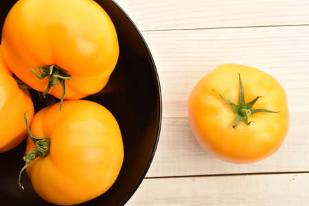 Fresh ripe, yellow tomatoes, close-up, on a painted wooden table.の写真素材
