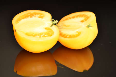 Fresh juicy yellow tomatoes, close-up, on a black background.の写真素材
