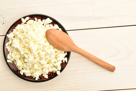 Fresh tasty, nutritious cottage cheese, close-up, on a painted wooden table.