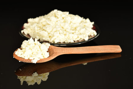 Fresh tasty, nutritious cottage cheese, close-up, on a black background.