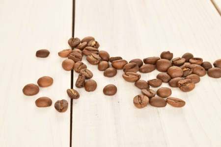 Fragrant roasted coffee grains, close-up, on a painted wooden table.の写真素材