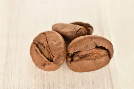 Fragrant roasted coffee grains, close-up, on a painted wooden table.の写真素材