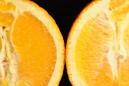 Ripe, organic orange, macro, on a black background.
