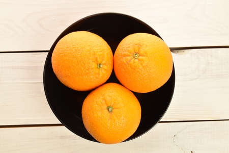 Bright yellow juicy, fresh, organic oranges, close-up, on a painted wooden table.の写真素材