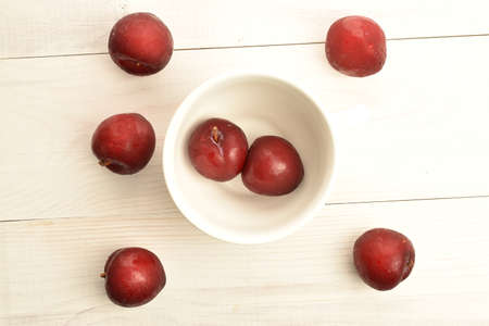 Juicy, tasty, organic red plum, close-up, on a painted wooden table.の写真素材