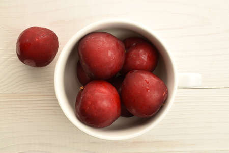 Juicy, tasty, organic red plum, close-up, on a painted wooden table.の写真素材