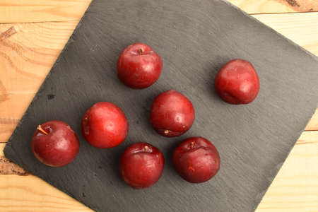 Juicy, tasty, organic red plum, close-up, on a wooden table.の写真素材