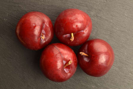 Juicy, tasty, organic red plum, close-up, on a serving plate of slate.の写真素材