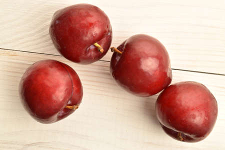 Juicy, tasty, organic red plum, close-up, on a painted wooden table.の写真素材