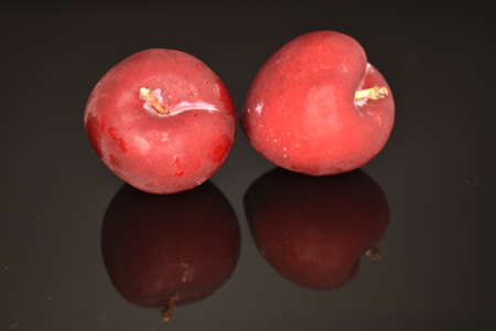 Juicy, tasty, organic red plum, close-up, on a black background.の写真素材