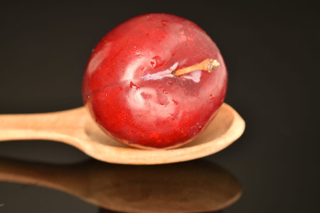 Juicy, tasty, organic red plum, close-up, on a black background.