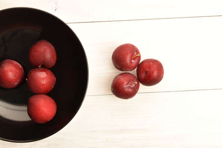 Juicy, tasty, organic red plum, close-up, on a painted wooden table.の写真素材