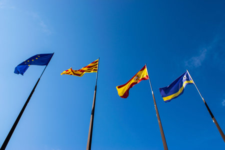 Official flags of the city of Salou, Spain, Catalonia and The European Union (EU) waving against a...