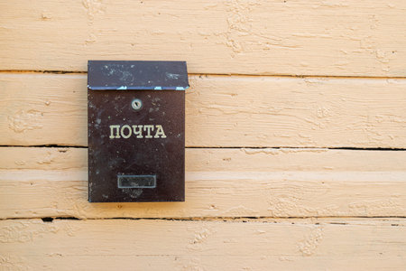 An old mail box hanging on a yellow wall. The inscription in Russian is Post, Mail