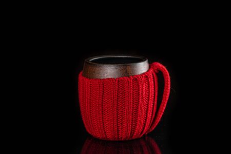 Cup in knitted cover with hot steaming tea isolated on blackの写真素材