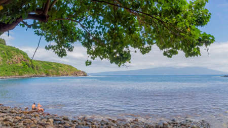 People relax on a rocky beach. People at the sea are preparing for swimming.の写真素材