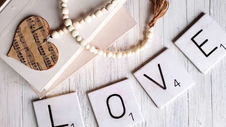 On beads hearts with notes. On a wooden floor. Below the cubes there is an inscription LOVE.の写真素材