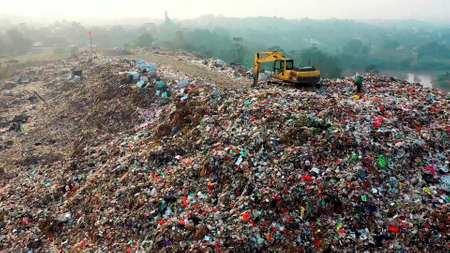 Tractor on a mountain of garbage. Tractor with a bucket on the garbage. Save the planet.の写真素材