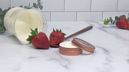 DIY beauty cream, white cream in a jar, strawberries in the backgroundの写真素材