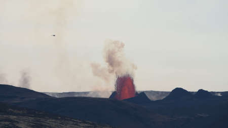 Eruption of a volcano against the background of a blue sky with clouds. Lava fountain. Smoke from the volcano.の写真素材