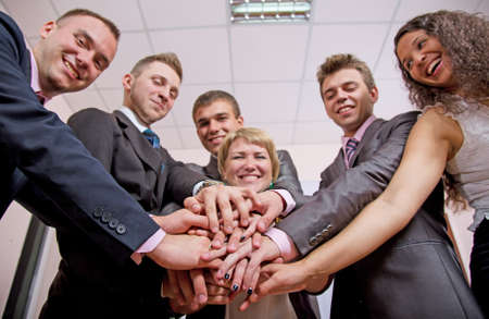 Friendly harmonious business team. Six business people join hands and smiling. Focus is on hands, but face expression is recognisable Friendly harmonious business team. Six business people join hands and smiling. Focus is on hands, but face expression is recognisable