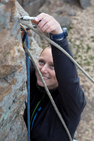 Blond female climber and her gear Smiling female climber links the rope to belaying devise