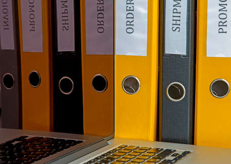 Office style reflections Several coloured folders reflecting in the screen of laptopの写真素材