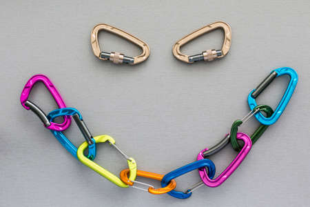 Smiley shape completed with alpine climbing carabiners Many coloured extreme climbing carabiners linked in the chain and forming the smiley shape. Two separate carabiners form an eyes of faceの写真素材