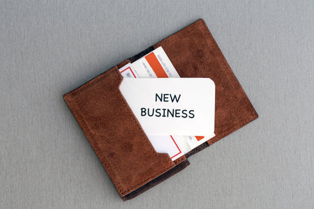 New business Conceptual composition with leather business-card folder, stack of colourful business cards and white business card with phrase New Business on foregroundの写真素材