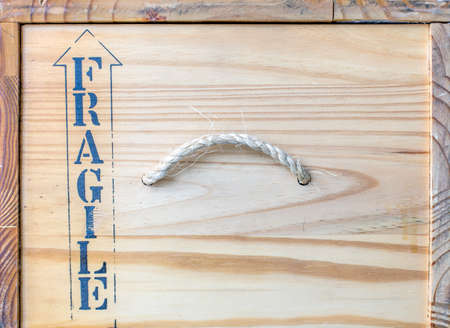 Side panel wooden delivery box natural wood transportation box hempen handle FRAGILE sign arrow indicating upper part well textured wood shape worm light brown colorの写真素材