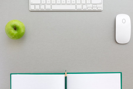 Working space in grey-green Creative office style composition with green apple and computer keyboard and mouse located on grey wooden desk. Top viewの写真素材
